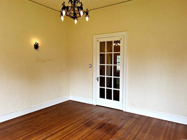 unfurnished room with wood-type flooring, a notable chandelier, and a textured ceiling