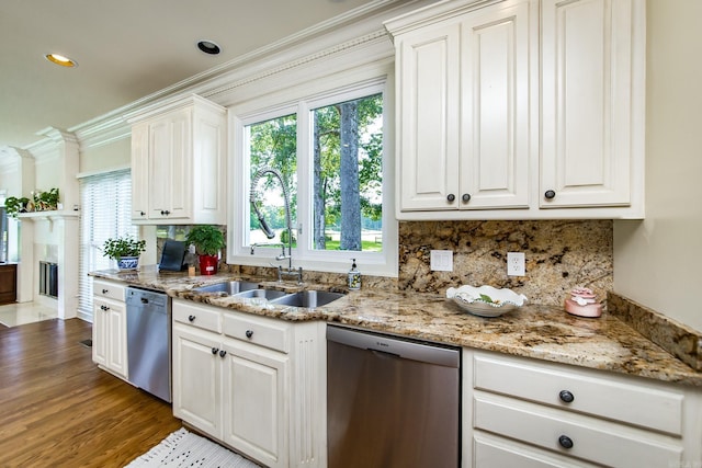 kitchen with dishwasher, backsplash, a sink, and light stone countertops