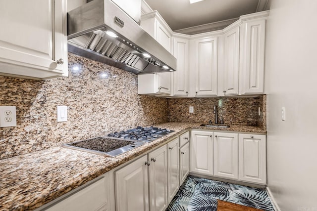 kitchen with stainless steel gas cooktop, decorative backsplash, white cabinets, a sink, and exhaust hood