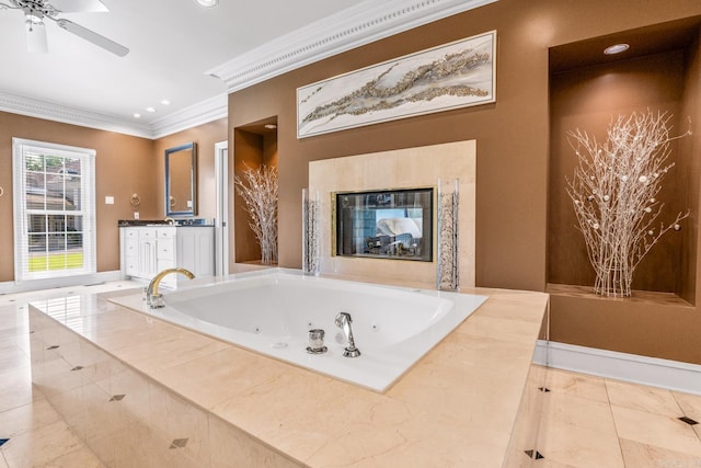 full bathroom featuring ceiling fan, vanity, a jetted tub, a glass covered fireplace, and crown molding