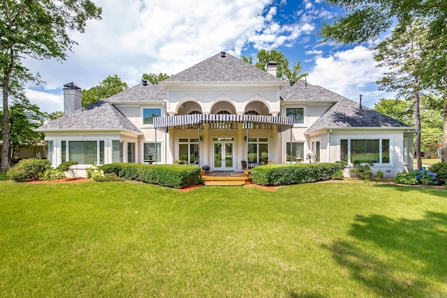 rear view of property featuring stucco siding, a chimney, a lawn, and french doors