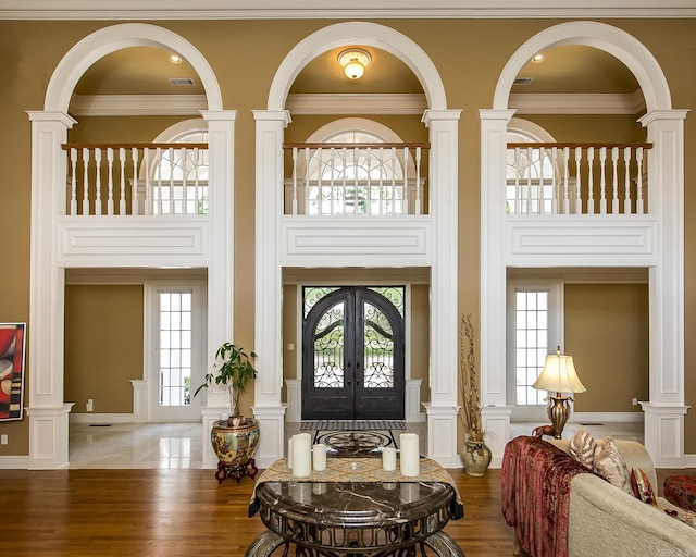 foyer entrance with ornamental molding, french doors, a decorative wall, and wood finished floors