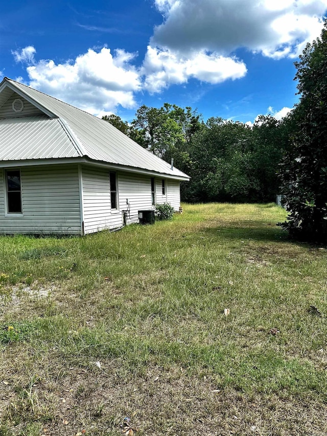 view of side of property with metal roof and a yard