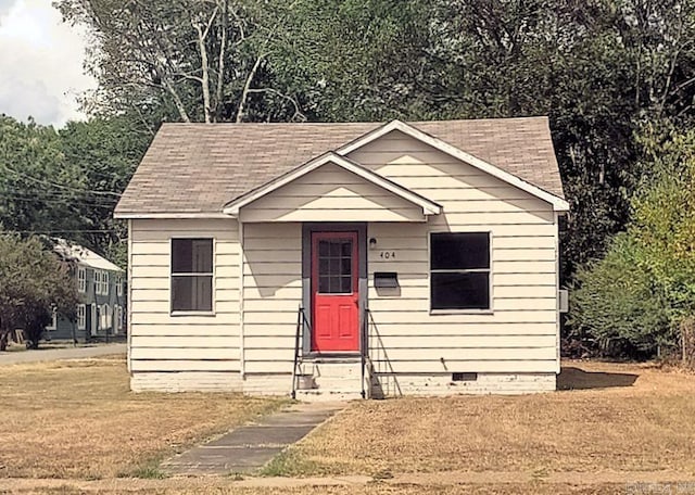 bungalow-style home with entry steps, crawl space, roof with shingles, and a front yard