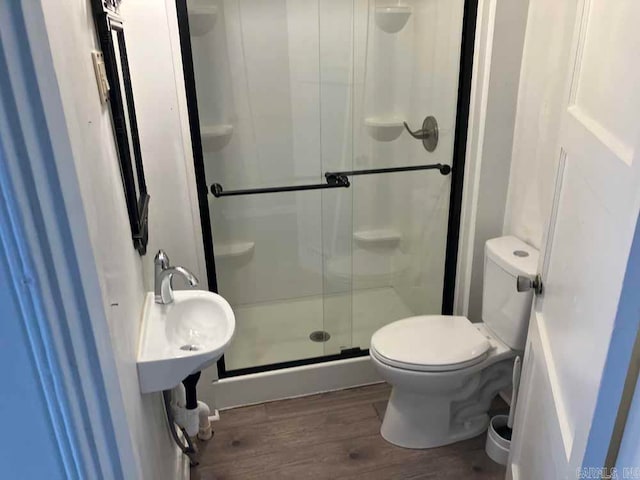 bathroom with toilet, hardwood / wood-style flooring, and a shower with door