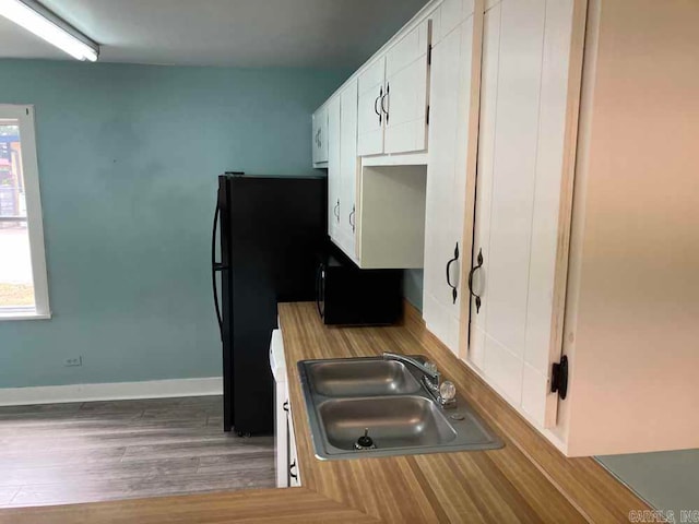 kitchen with sink, light wood-type flooring, and white cabinets