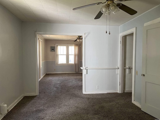 unfurnished room featuring a wainscoted wall, carpet, and ceiling fan