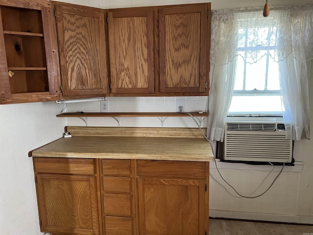 kitchen featuring cooling unit, tile walls, light countertops, tile patterned floors, and brown cabinetry