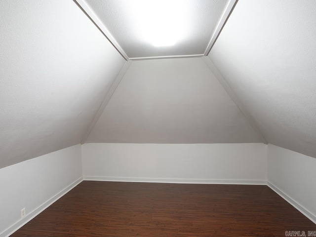 additional living space with dark hardwood / wood-style floors and vaulted ceiling