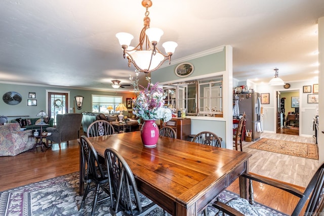 dining space featuring crown molding, wood-type flooring, and an inviting chandelier