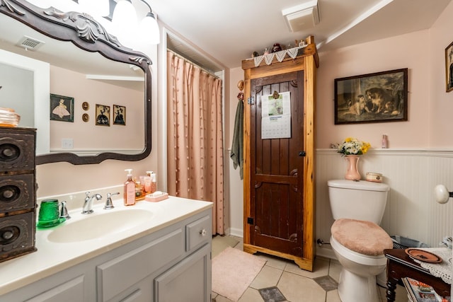 bathroom with wood walls, tile patterned flooring, toilet, and vanity