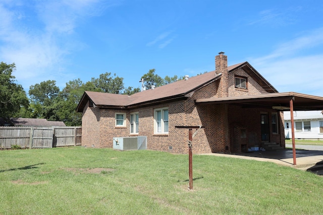 back of property with central AC unit and a lawn