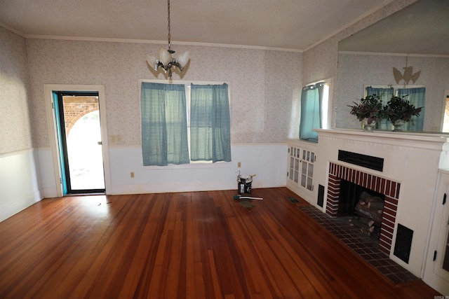 unfurnished living room featuring a textured ceiling, dark hardwood / wood-style floors, an inviting chandelier, a fireplace, and ornamental molding