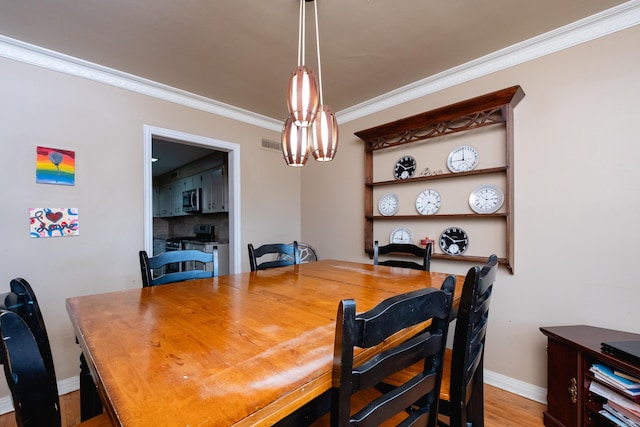 dining area featuring light wood-type flooring, a chandelier, and ornamental molding