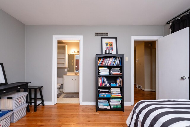 bedroom with light wood-type flooring and ensuite bathroom