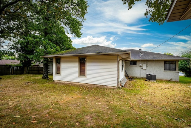 rear view of property featuring central AC and a lawn