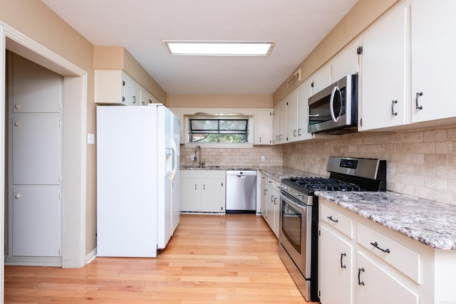 kitchen featuring light wood-type flooring, sink, stainless steel appliances, and white cabinets