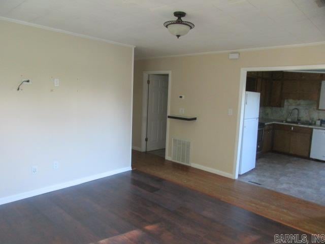 unfurnished living room with sink, dark hardwood / wood-style flooring, and ornamental molding