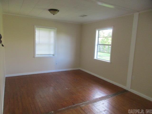 spare room featuring ornamental molding and dark hardwood / wood-style flooring