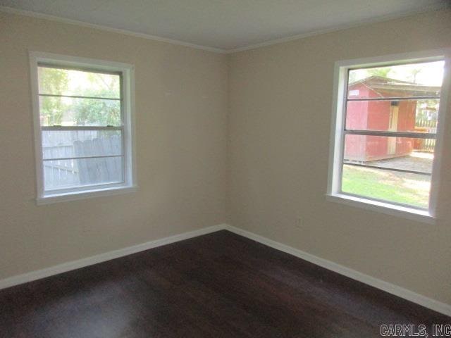 unfurnished room with dark wood-type flooring and ornamental molding