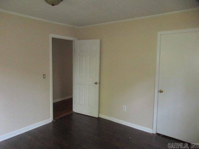 unfurnished bedroom with crown molding and dark hardwood / wood-style floors