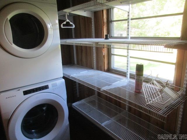 laundry room with a wealth of natural light and stacked washer / drying machine