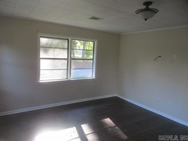 empty room featuring hardwood / wood-style floors and crown molding