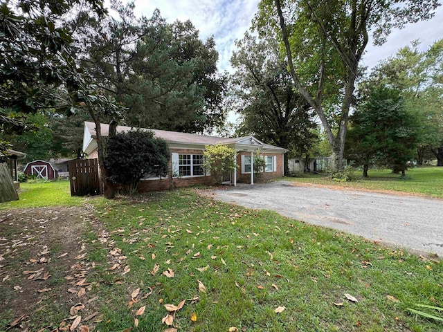 ranch-style house featuring a storage unit and a front yard