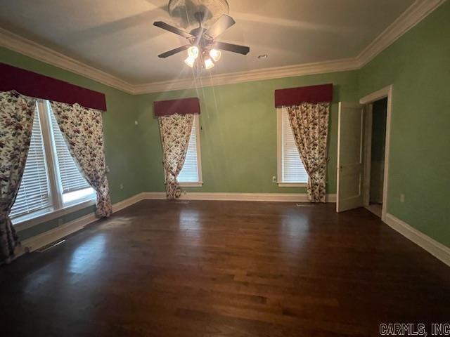 empty room with plenty of natural light, crown molding, baseboards, and wood finished floors