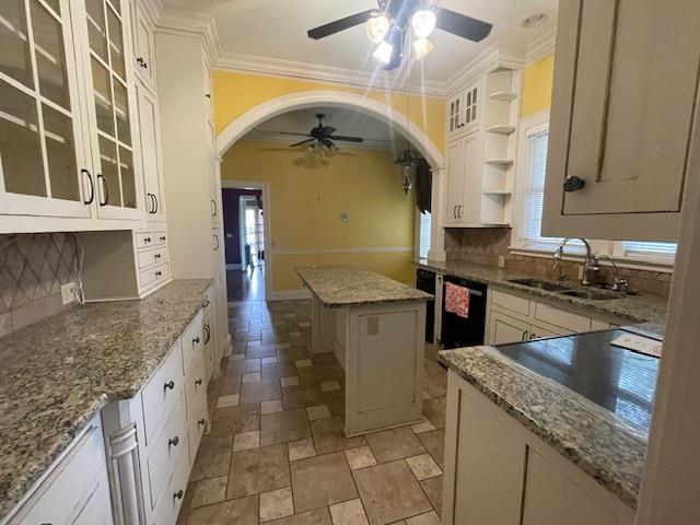 kitchen with a sink, black dishwasher, arched walkways, a ceiling fan, and open shelves