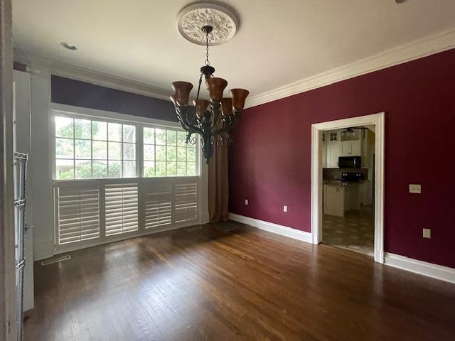 spare room with wood finished floors, baseboards, and ornamental molding