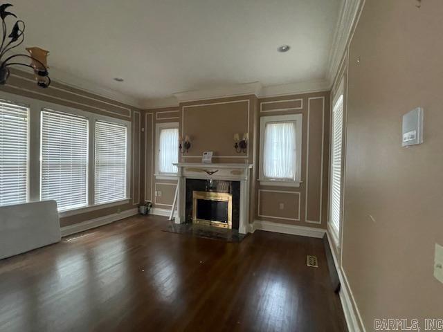 unfurnished living room featuring wood finished floors, crown molding, a fireplace, and baseboards