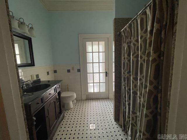 bathroom featuring toilet, vanity, decorative backsplash, tile walls, and a shower with curtain