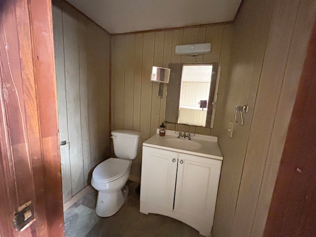 bathroom with wooden walls, vanity, and toilet