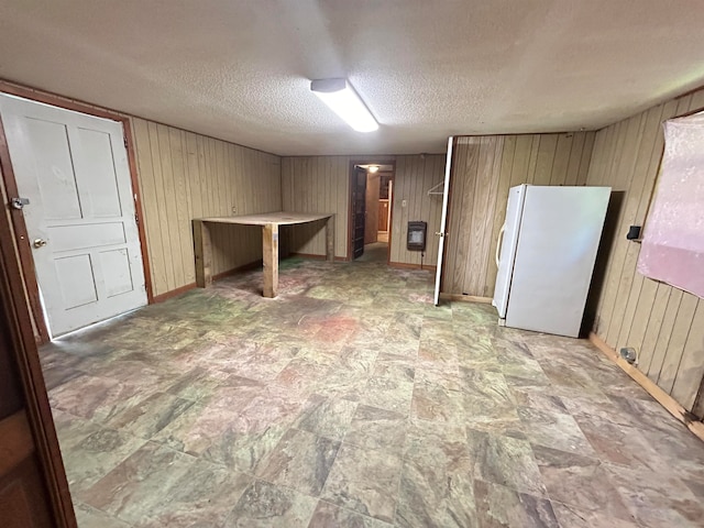 interior space featuring wood walls, white refrigerator, and a textured ceiling