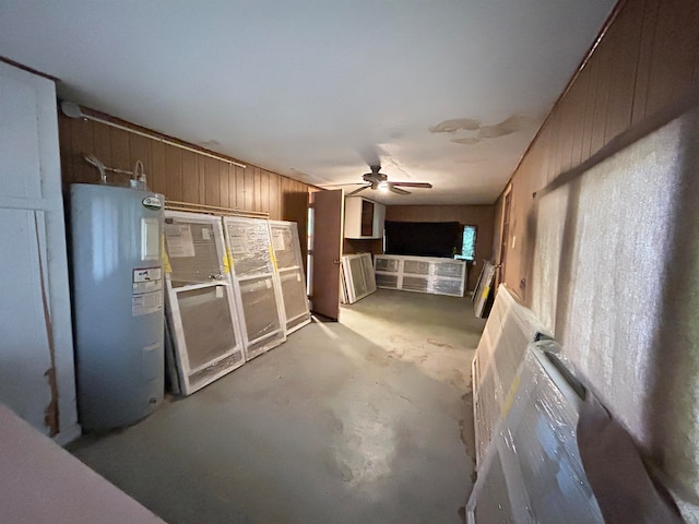 kitchen featuring wooden walls, concrete flooring, ceiling fan, and electric water heater