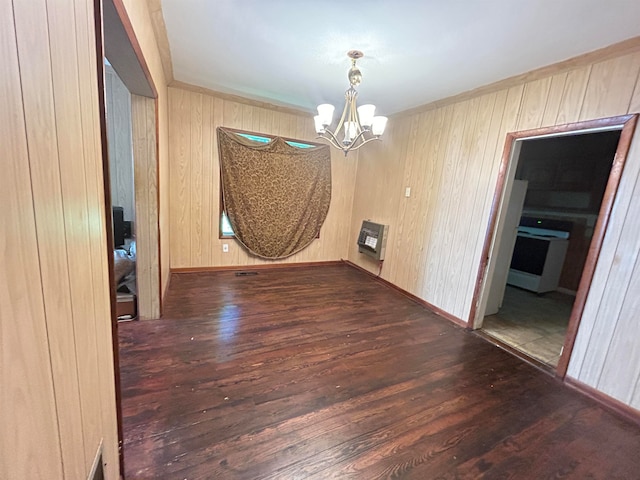 unfurnished dining area with heating unit, wooden walls, a chandelier, and dark wood-type flooring