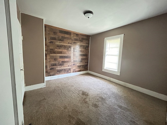 carpeted empty room featuring wooden walls