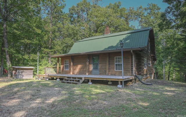 back of property with a wooden deck, a lawn, and a storage shed