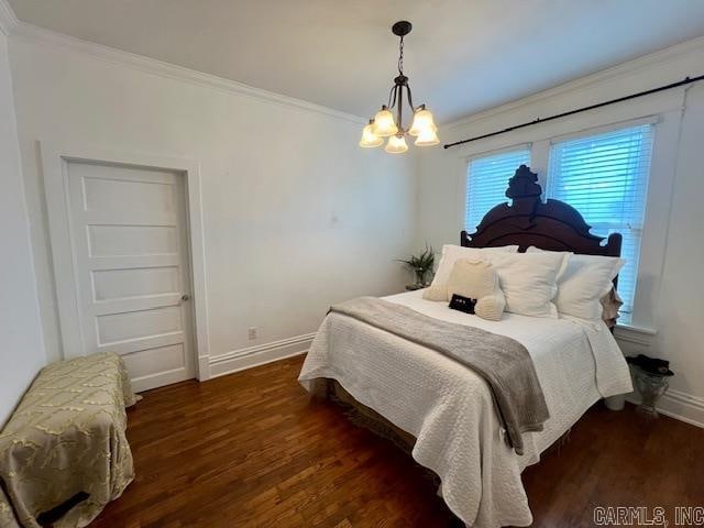 bedroom with a notable chandelier, crown molding, baseboards, and wood finished floors