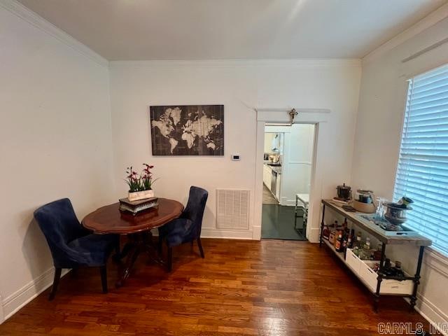 dining area featuring baseboards, visible vents, wood finished floors, and ornamental molding