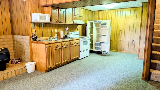 kitchen with white appliances, sink, light colored carpet, and wooden walls