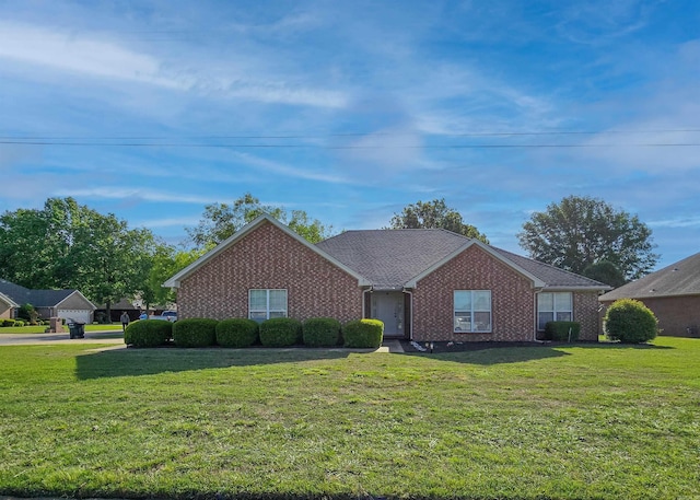 ranch-style home featuring brick siding, roof with shingles, and a front yard