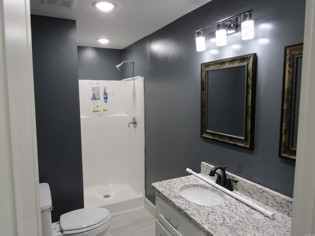 bathroom with vanity, tile patterned flooring, toilet, and a shower