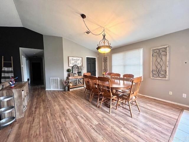 dining space featuring vaulted ceiling and hardwood / wood-style flooring