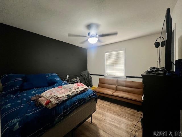 bedroom with ceiling fan, light hardwood / wood-style floors, and a textured ceiling