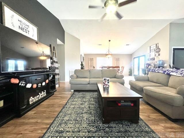 living room featuring dark wood-type flooring, ceiling fan, and vaulted ceiling