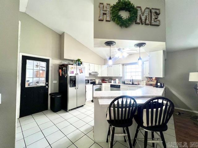 kitchen with pendant lighting, stainless steel appliances, sink, kitchen peninsula, and white cabinetry