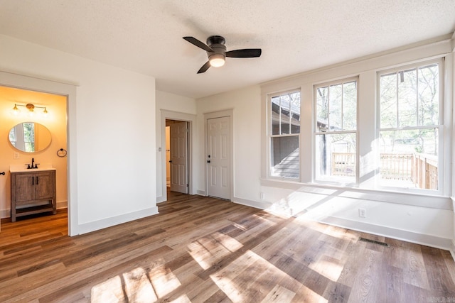 interior space with ceiling fan, hardwood / wood-style flooring, sink, and a textured ceiling