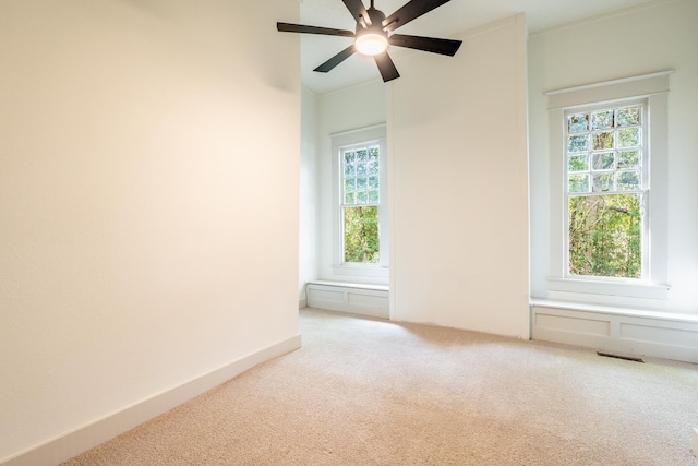 empty room with ceiling fan, light colored carpet, and crown molding